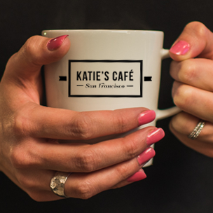 Person holding mug with logo that says Katie's Cafe